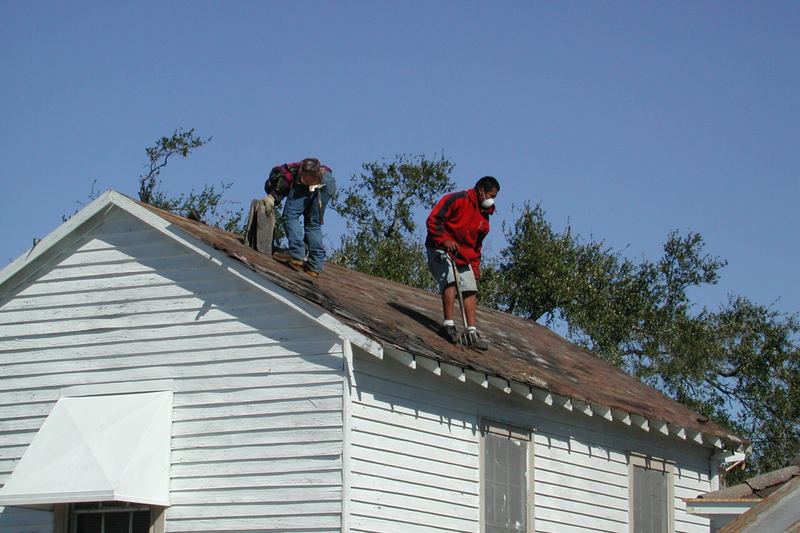 Two roofers re-roofing a timber house